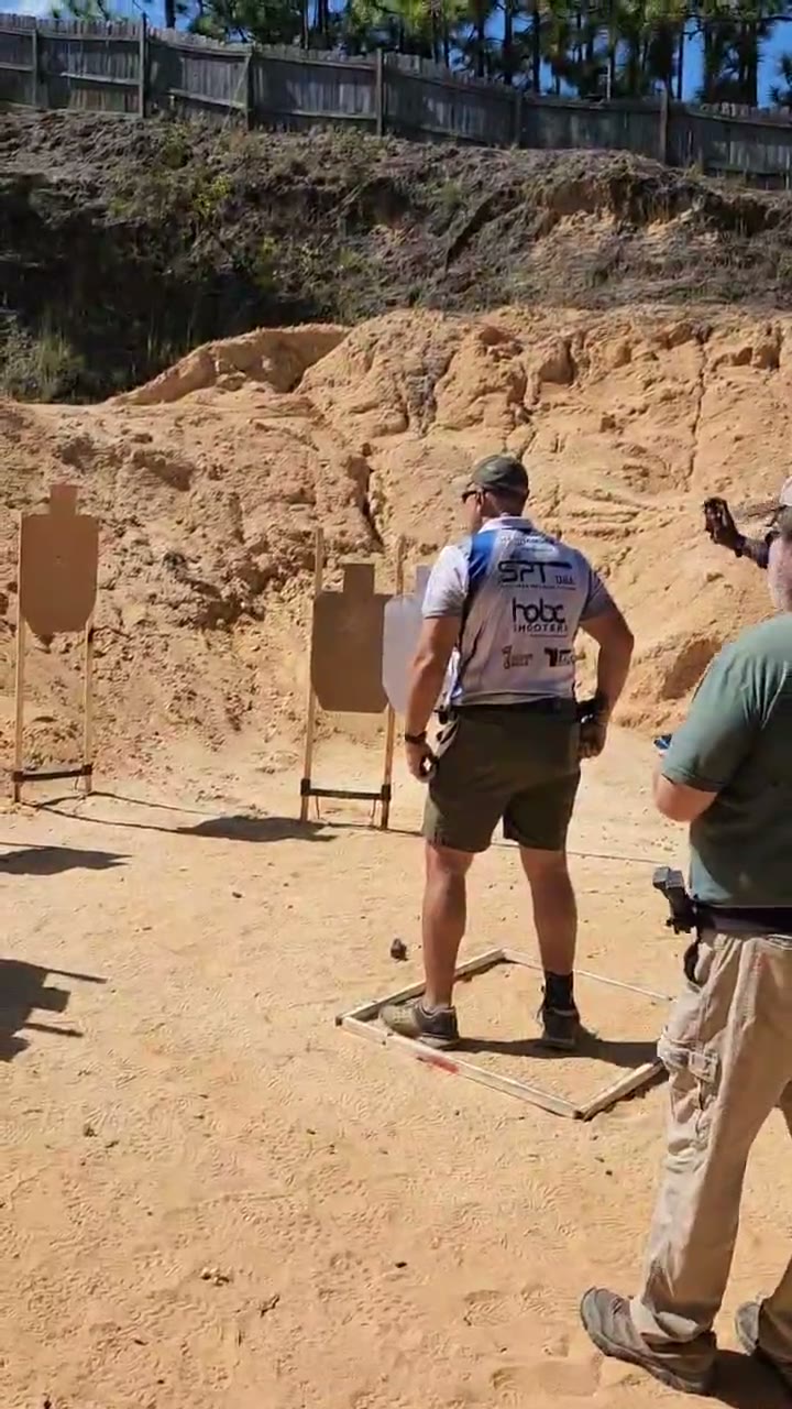 Team shooter squared up on paper targets with the range officer behind